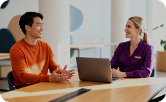 Two professionals discussing Exely referral program at a desk with a laptop