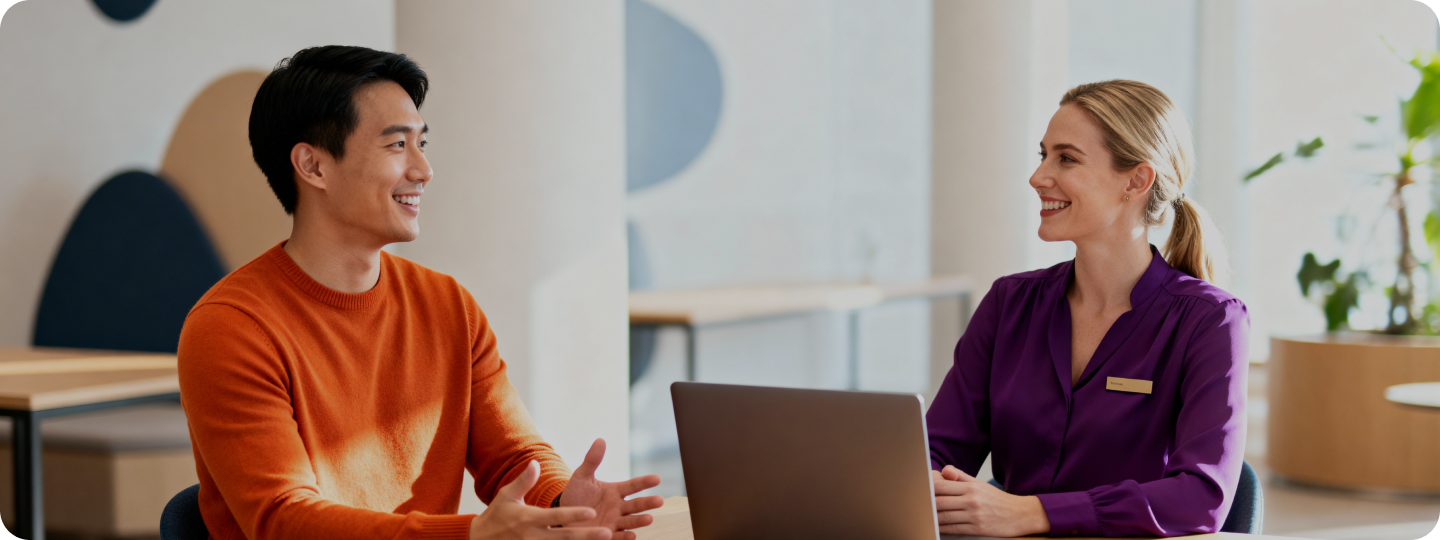 Two professionals discussing Exely referral program at a desk with a laptop